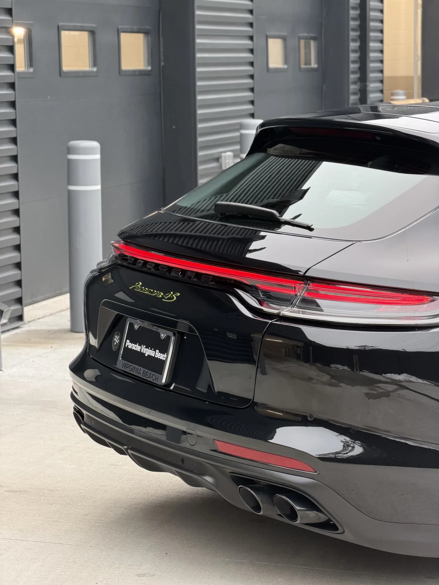 Rear quarter of a Porsche Panamera 4S after paint enhancement, reflecting the dealership behind it