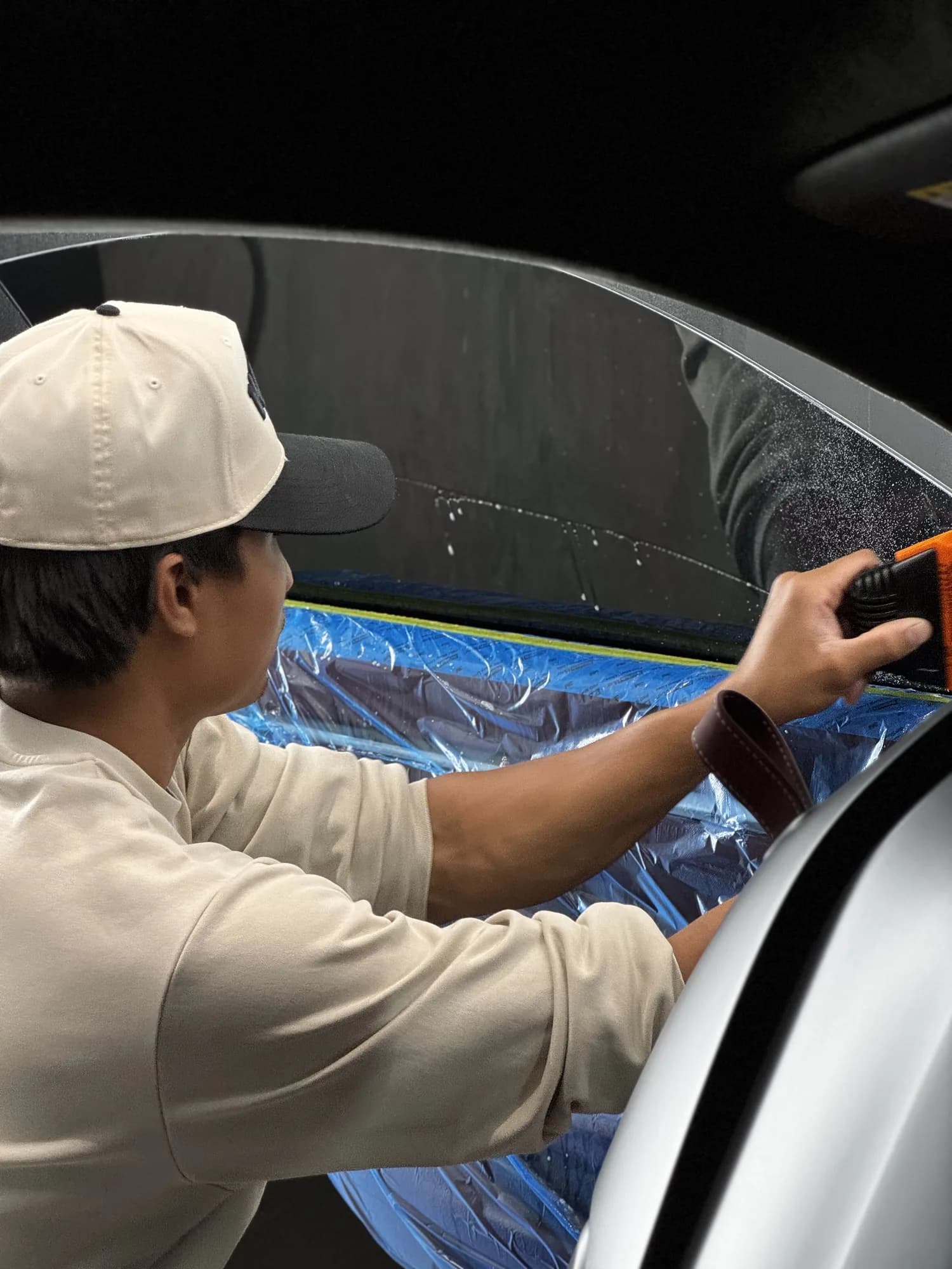 A Blackbird technician laying window film across door glass with a squeegee